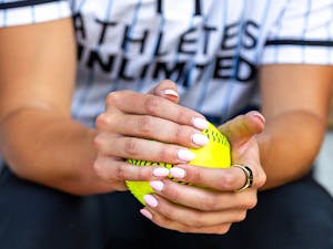 Player holding a softball with pink nail polish