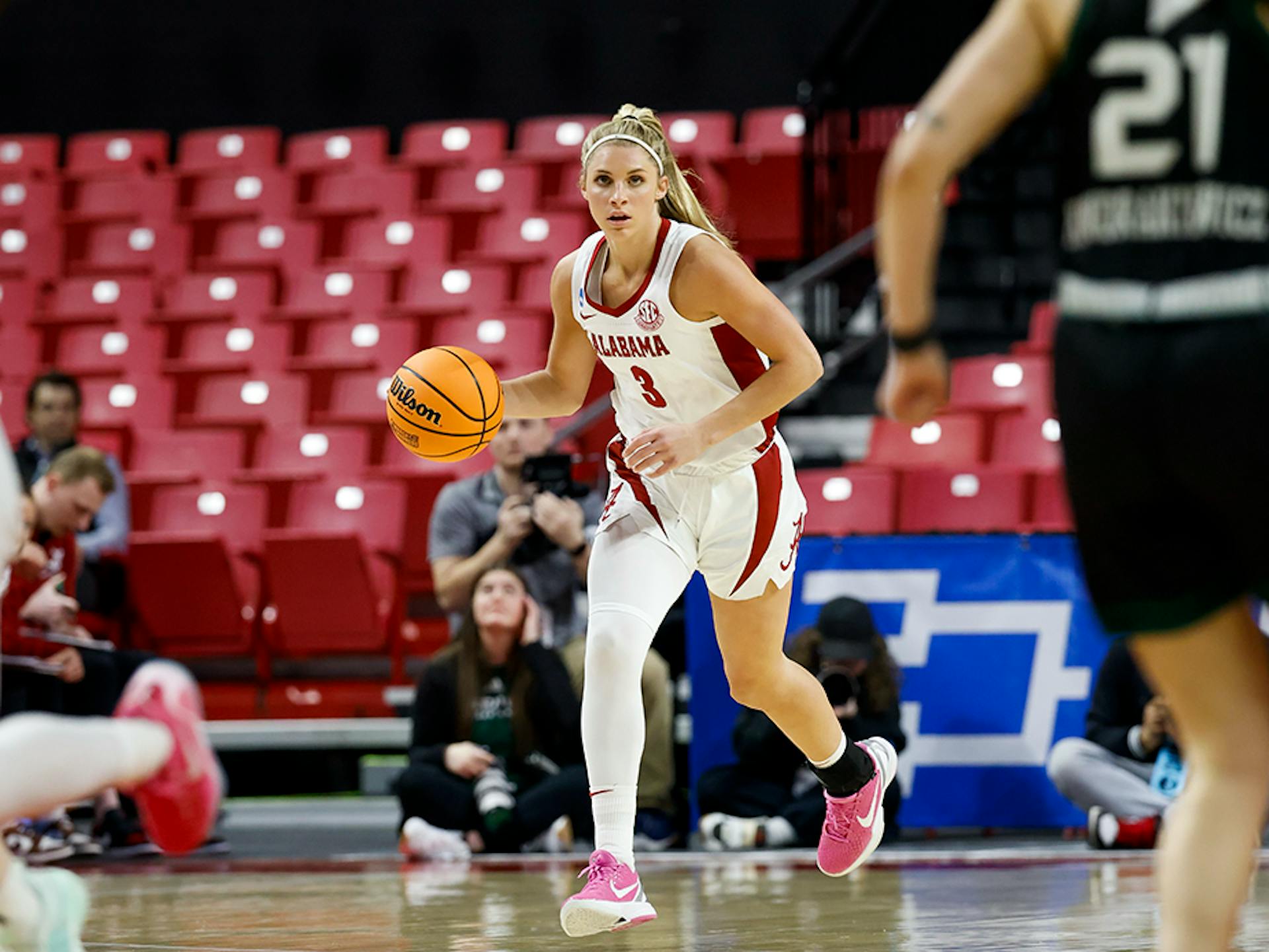 Sarah Ashlee Barker, wearing her red and white Alabama uniform, dribbles a basketball up the court.